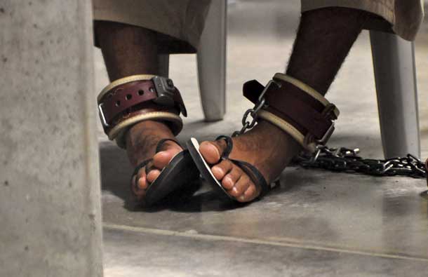 In this photo, reviewed by a U.S. Department of Defense official, a Guantanamo detainee's feet are shackled to the floor as he attends a 