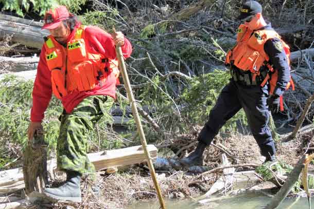 Master Corporal Isaac Barkman, left, and an OPP constable negotiate heavy bush.