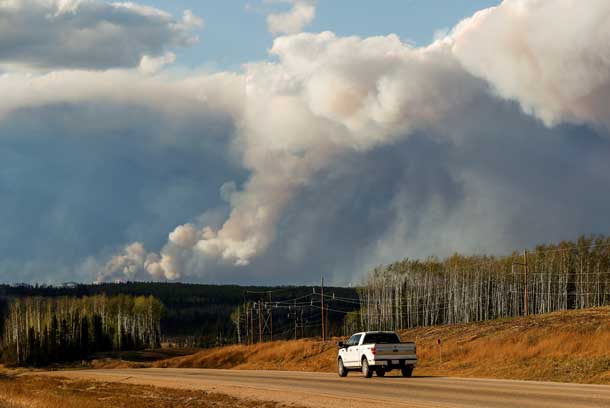 Smoke billows from the Fort McMurray wildfires as a truck drives down the highway in Kinosis, Alberta, Canada, May 5, 2016. REUTERS/Mark Blinch