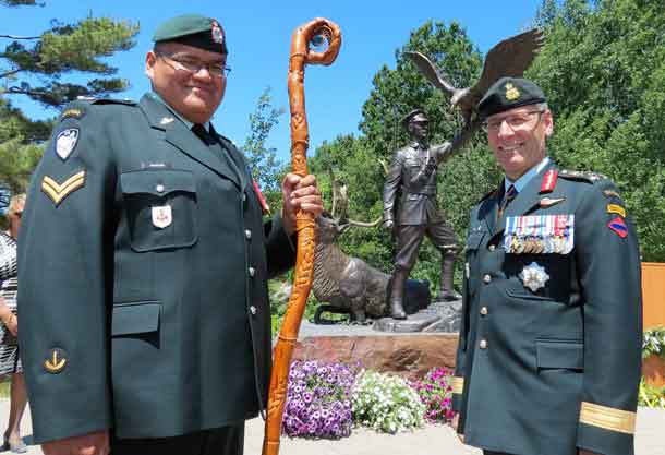 Corporal Paul Nakogee of the Algonquin Regiment, holding the regiment's eagle staff, with Lieutenant-General Marquis Hainse, commander of the Canadian Army, after a statue honouring Sergeant Francis Pegahmagabow, Canada's most highly decorated indigenous soldier, was unveiled in Parry Sound on Nationsal Aboriginal Day. Corporal Nakogee, from Attawpiskat,is studying in North Bay.