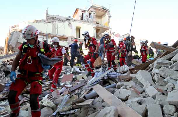 Rescuers walk through rubble following the earthquake in Amatrice, central Italy. REUTERS/Stefano Rellandini