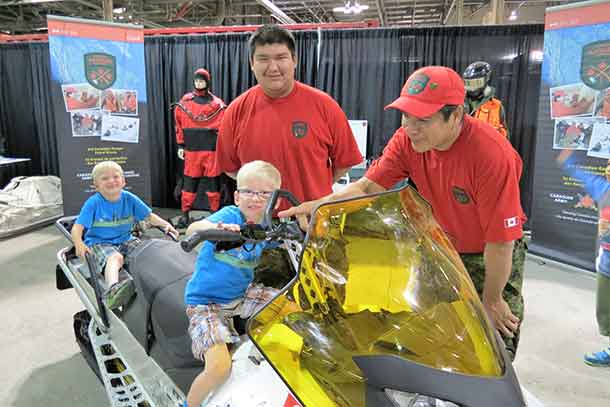 Corporal Peter Echum and Sergeant Jason Roundhead with two young visitors to the Canadian Armed Forces display at the Canadian National Exhibition in Toronto`