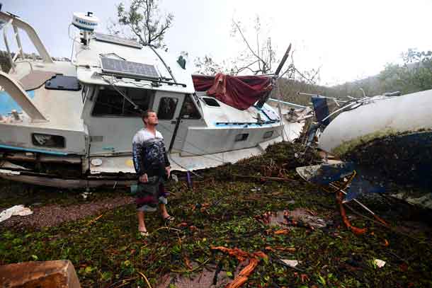Local resident Bradley Mitchell inspects the damage to a relative's boat after it smashed against the bank after Cyclone Debbie passed through the township of Airlie Beach, located south of the northern Australian city of Townsville. AAP/Dan Peled/via REUTERS