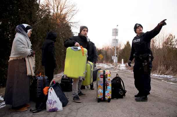 A group that claimed to be from Turkey is met by a Royal Canadian Mounted Police (RCMP) officer after they crossed the U.S.-Canada border illegally leading into Hemmingford, Quebec, Canada March 6, 2017.  REUTERS/Christinne Muschi/File Photo