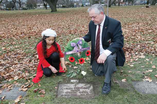 Rob Larman, a leg amputee, and Tiffany Ross, a left arm amputee and member of The War Amps Child Amputee (CHAMP) Program, lay a rose at the grave of Curley Christian, who lost all four limbs in the Vimy Ridge Battle, at Prospect Cemetery in Toronto, ON, Canada. (Photo by John E. Sokolowski/WarAmps)