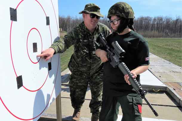 Master Warrant Officer James Currier, left, checks Junior Canadian Ranger Claudia Albany's shots on the target.