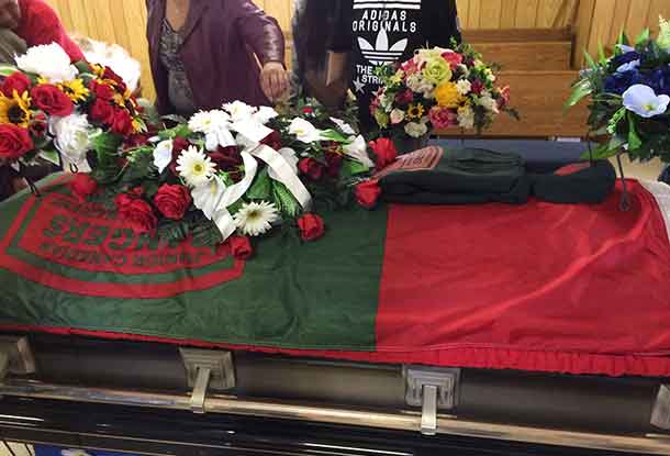 A Junior Canadian Ranger flag and Junior Ranger cap and sweater drape the casket of Josiah Begg