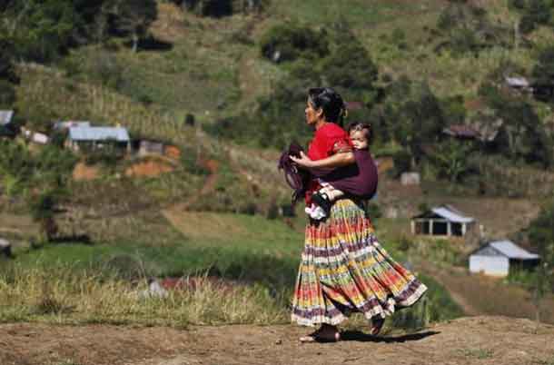 An indigenous woman carries a child on her back while walking down a road in the village of Pambach, in the Alta Verapaz region, about 209 km (130 miles) from Guatemala City, February 20, 2014. REUTERS/Jorge Dan Lopez