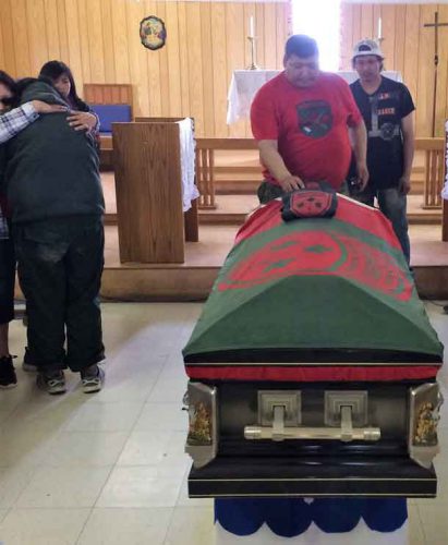 Ranger Sergeant Spencer Anderson touches the casket while a sobbing Junior Canadian Ranger is comforted.