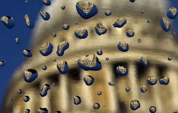 St Paul's Cathedral is seen refracted in raindrops on a metal plaque following heavy rainfall in the City of London, Britain December 15, 2014. REUTERS/Toby Melville