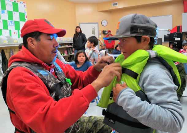 Ranger Redfern Wesley puts a life jacket on a young student. Photo - Sgt Peter Moon