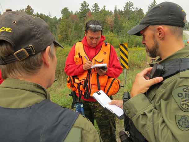 Master Corporal Shaun Kakegamic takes notes while two Ontario Provincial Police training officers tell him where to take a search part during search and rescue training. Credit: Sergeant Peter Moon, Canadian Rangers