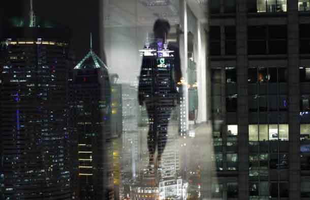 A woman is reflected in a window of an office in the financial district of Pudong in Shanghai September 22, 2011. REUTERS/Carlos Barria