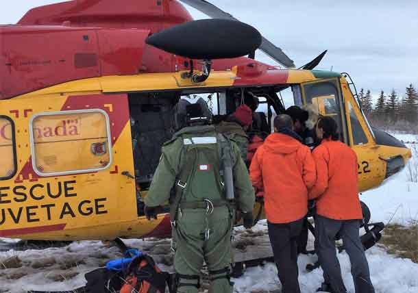 The injured snowmobiler is loaded on to an RCAF helicopter.