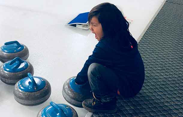 Curling fans of all ages are watching the action. Here Lamarith tests out how heavy a curling stone really is. - James Murray photo.