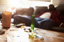 Man Slumped On Sofa With Drug Paraphernalia In Foreground