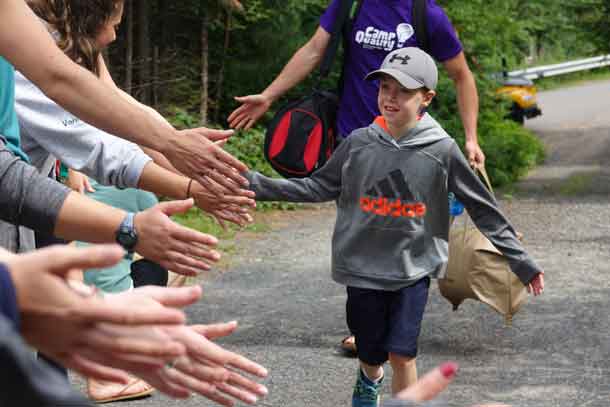 Camper Ryder arriving at camp and making his way down the line of welcome high-fives from our volunteer staff.