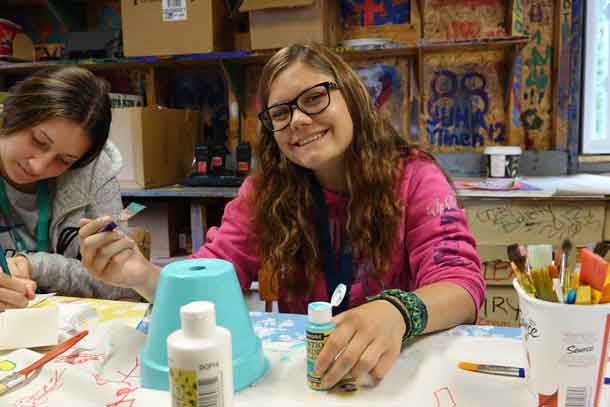 Camper Kaija finishing up her crafts from this week in the craft shack with volunteer Jaqueline.