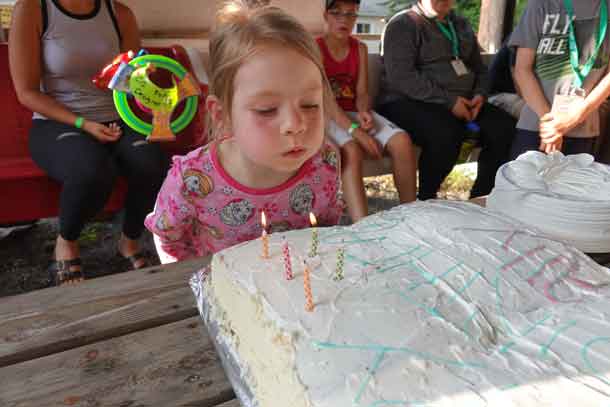 Camper Ally blowing out the candles on the birthday cake made to celebrate her special day.