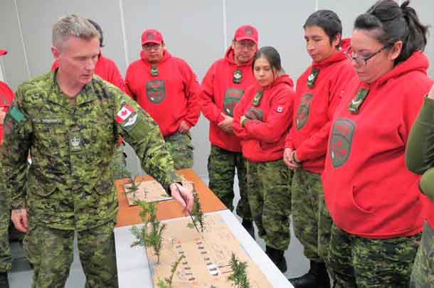 Warrant Officer Christopher Thomson uses an improvised model to show Canadian Rangers how to make an emergency aircraft landing strip.