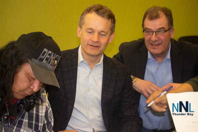 Cat Lake Chief Matthew Keewaykapow signs agreement as Minister O'Regan and Bob Nault watch
