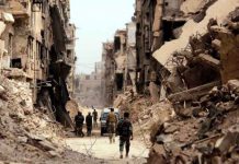 Three Syrians arrested in Germany and France for suspected crimes against humanity Soldiers walk past damaged buildings in Yarmouk Palestinian camp in Damascus, Syria May 22, 2018. REUTERS/Omar Sanadiki