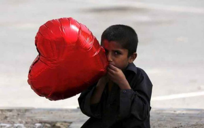 A boy inflates a heart-shaped balloon to sell on Valentine's Day in Karachi, Pakistan February 14, 2016. REUTERS/Akhtar Soomro