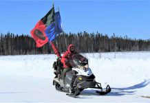 Sandy Lake Shivers Under Clear Skies and Intense Arctic Cold Ranger Quinton Anishinabie leads a territorial surveillance patrol while flying Canadian Ranger and Sandy Lake First Nation flags on his snowmobile.
