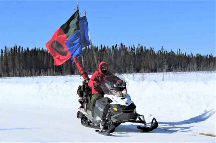 Cdn-Rangers-snowmobile-March-30-2019 Ranger Quinton Anishinabie leads a territorial surveillance patrol while flying Canadian Ranger and Sandy Lake First Nation flags on his snowmobile.
