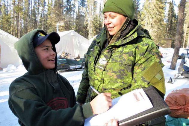Junior Canadian Ranger Jayvan Ross of Muskat Dam signs an attendance sheet for Sergeant Eva Clarke, an army instructor.