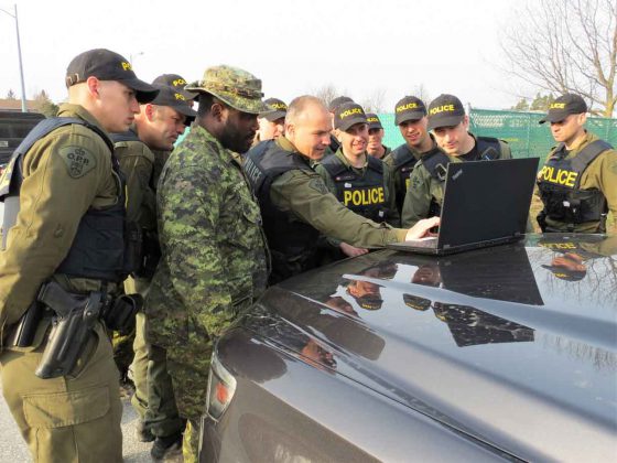 Sergeant Eric Scott and OPP officers look at a computer map of an area to be searched.