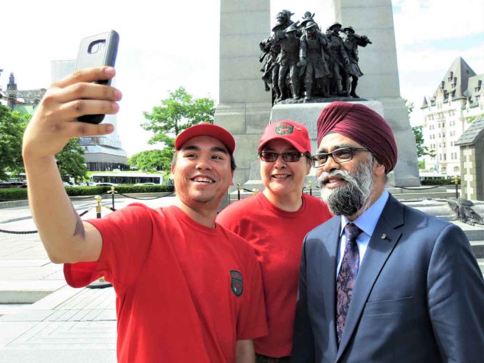 Corporal Angus Sutherland, left, and Master Corporal Paula Nakogee, centre, get a selfie with National Defence Minister Harjit Sajjan in front of the National War Memorial in Ottawa.