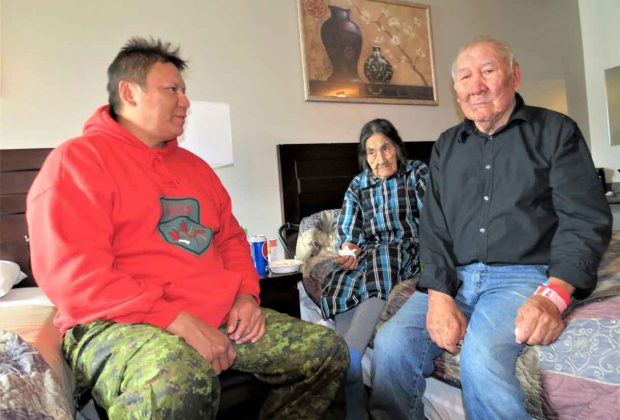 Ranger Bennett Quill, left, speaks in Ojibwa with Pikangikum evacuees and elders Aipi King and her husband, John George King, in a hotel room in Sioux Lookout. The Kings are both 86