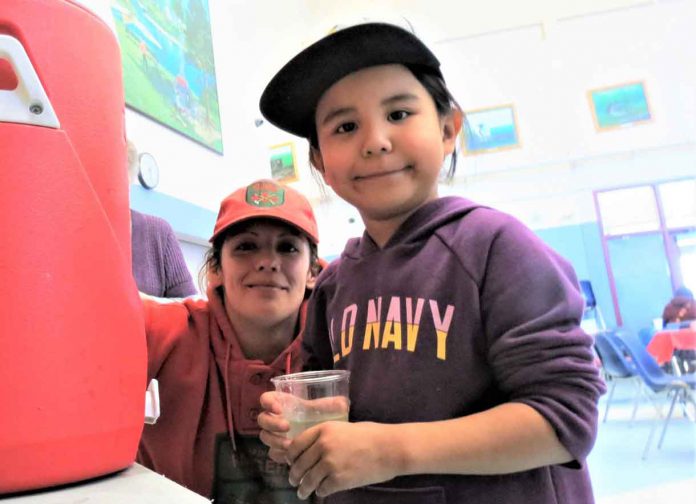Ranger Carla Slobozian helps Pikangikum evacuee Patience Turtle, five, to get a drink at Pelican Falls First Nations School, near Sioux Lookout