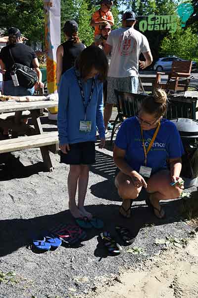 Camper Kassi trying her hands (or feet!) at trying to identify some mystery animal tracks in the sand with Tempest from Let’s Talk Science!