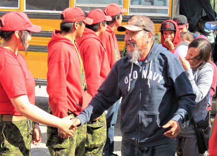 An elder thanks a Canadian Ranger as he walks from a bus to a waiting evacuation plane.