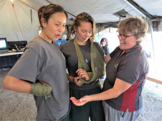 Nancy Hutchinson, right, a St. John Ambulance first aid instructor, teaches two Junior Canadian Rangers how to make a sling. Photo credit Sergeant Peter Moon, Canadian Rangers