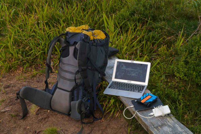 Portable technology, solar panel, tablet, laptop and backpack in a forest