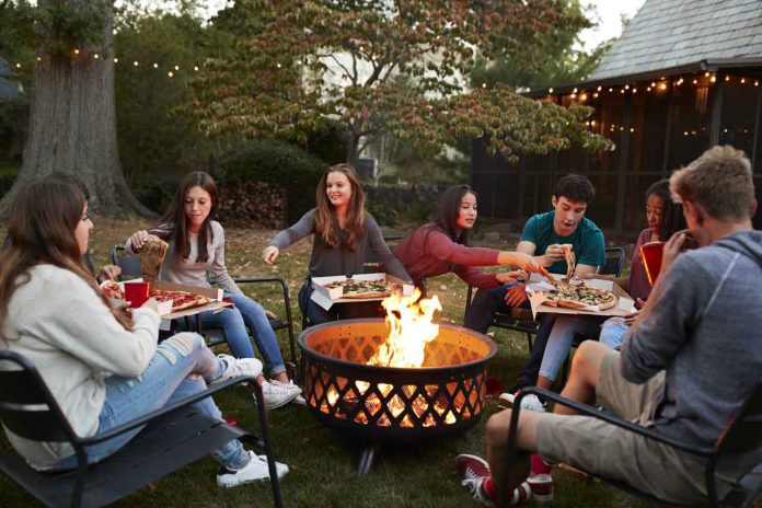 Teenage friends sit round a fire pit