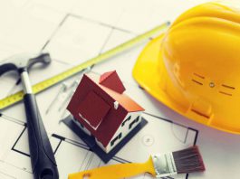 5 Ways Construction Companies Ensure Insulation Meets Energy Codes and Sustainability architecture, building, construction, real estate and home concept - close up of living house model on blueprint with repair tools