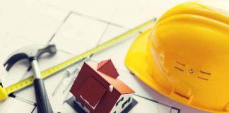 5 Ways Construction Companies Ensure Insulation Meets Energy Codes and Sustainability architecture, building, construction, real estate and home concept - close up of living house model on blueprint with repair tools