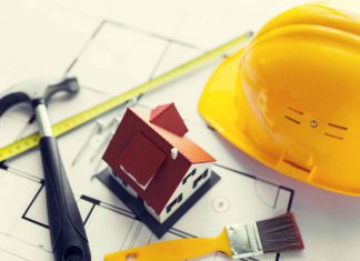 5 Ways Construction Companies Ensure Insulation Meets Energy Codes and Sustainability architecture, building, construction, real estate and home concept - close up of living house model on blueprint with repair tools