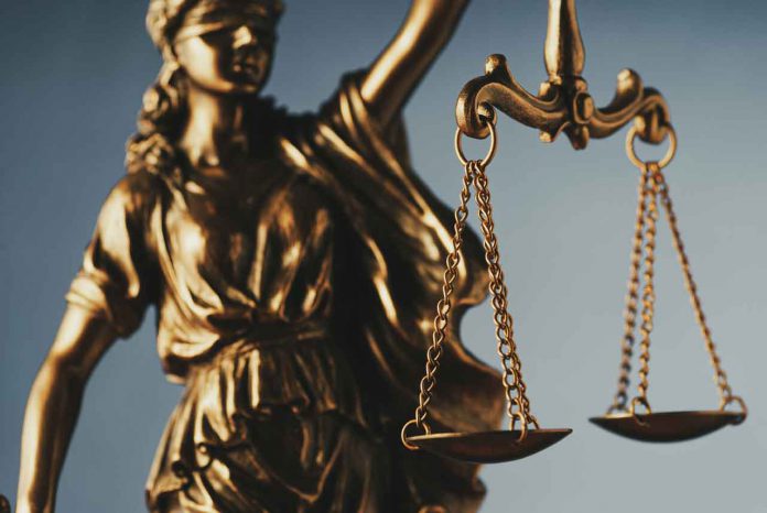 Figure of Justitia or Justice holding the scales of justice with close up focus to the scales symbolic of the law over grey