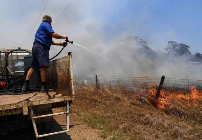 Tinonee resident Brian Acheson sets up his tip truck as a makeshift fire truck to assist residents fighting spot and grass fires in the Hillville area near Taree, NSW, Australia, November 13, 2019. AAP Image/Dean Lewins/via REUTERS