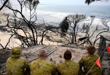 Australia Fires a Red Alert on Climate Change Soldiers sit on a beach amongst burnt trees where people had previously taken shelter during a fire on New Year's Eve in Mallacoota, Australia January 10, 2020. REUTERS/Tracey Nearmy
