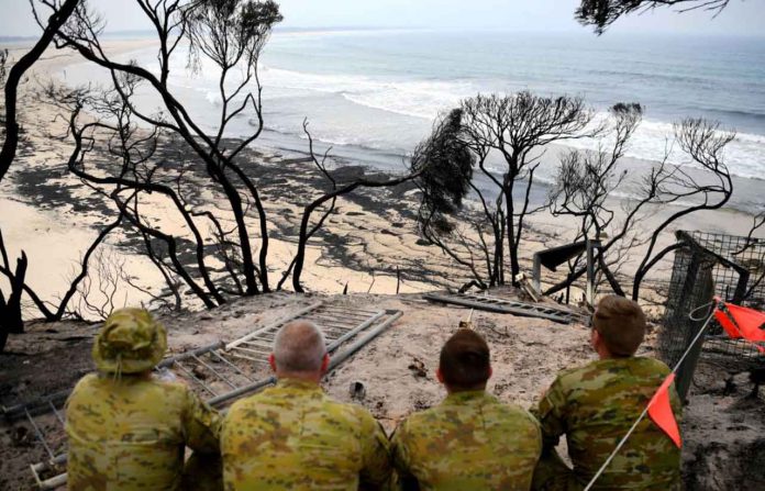 Soldiers sit on a beach amongst burnt trees where people had previously taken shelter during a fire on New Year's Eve in Mallacoota, Australia January 10, 2020. REUTERS/Tracey Nearmy