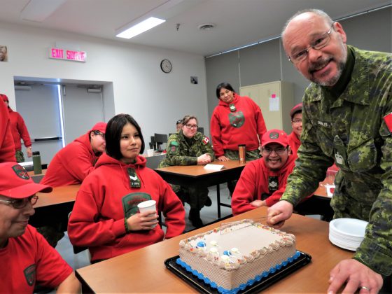 Warrant Officer Sheldon DeWolfe, an army instructor, prepares to cut a celebratory cake with a ruler for the Canadian Ranger students.