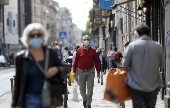 People wearing protective masks walk in an increasingly busy street, amid the coronavirus disease (COVID-19) outbreak, in Milan, Italy April 18, 2020. REUTERS/Daniele Mascolo