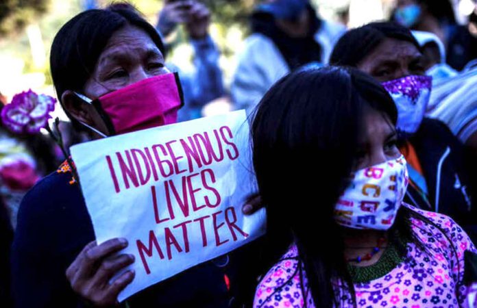 FILE PHOTO: Demonstrators wearing face masks protest in front of a military battalion, against the reported rape of an Embera Chami indigenous girl by soldiers, in Bogota, Colombia June 29, 2020. REUTERS/Luisa Gonzalez/File Photo