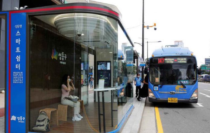 A woman wears a mask inside a glass-covered bus stop in which a thermal imaging camera, UV sterilizer, air conditioner, CCTV and digital signage are set, to avoid the spread of COVID-19 in Seoul, South Korea, August 14, 2020. REUTERS/Heo Ran